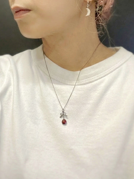Person wearing a necklace with a red garnet silver pendant 